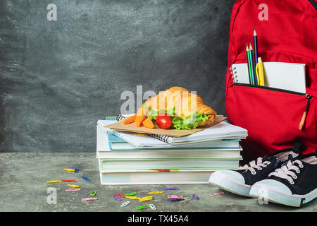 Sandwich Ausbildung liefert Notebooks Stifte Buntstifte rot Rucksack Sneakers auf dem Hintergrund der Kreidetafel. Das Konzept der Schule. Selektive fo Stockfoto