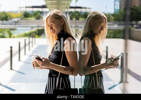 Blonde junge Frau mit Kaffee zu gehen, Zelle Telefon Stockfoto