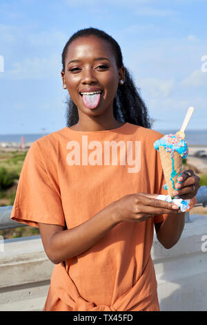 Porträt der jungen Frau mit Hellblau icecream Scoop zeigt Zunge Stockfoto