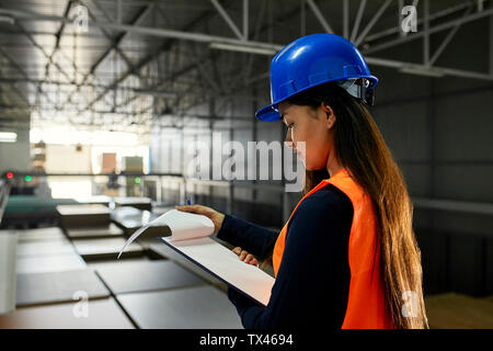 Weibliche Arbeitnehmer, Prüfung von Dokumenten in Werks- und Lagergebäude Stockfoto