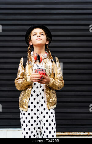 Portrait von Mädchen mit Smartphone zu tragen hat, goldene Pailletten Jackett und Polka Dot jumpsuit Denken Stockfoto