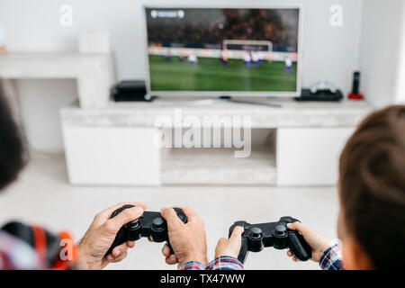 Vater und Sohn spielen Computer Spiel zusammen zu Hause, Teilansicht Stockfoto