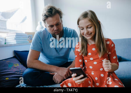 Vater und über Handy zu Hause Tochter Stockfoto