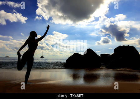 Seychellen, Mahe, Takamaka Beach, Silhouette von Frau Yoga am Strand Stockfoto