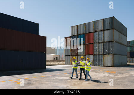 Arbeitnehmer zusammen gehen in der Nähe von Stack von Frachtcontainern auf Industrial Site Stockfoto