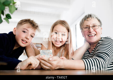 Portrait von Happy Großmutter und Enkel mit Handy zu Hause Stockfoto