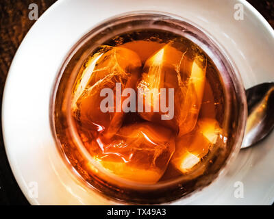 Blick von oben auf die kalten gebrühten Kaffee mit Eiswürfel in ein klares Glas plased auf einer weißen Platte Stockfoto