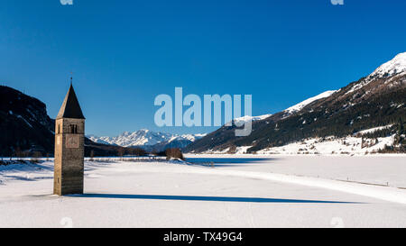 Italien, Vinschgau, versunkene Turm in gefrorenen Lago di Resia im Winter Stockfoto