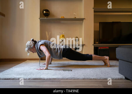 Reife Frau Yoga Übung im Wohnzimmer Stockfoto