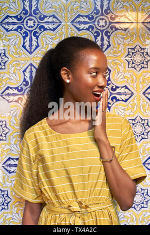 Überrascht junge Frau an einem gefliesten Wand Stockfoto