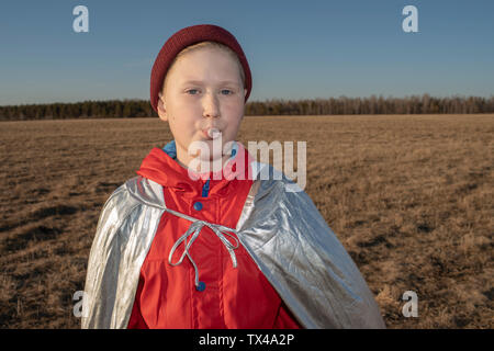 Portrait der Junge verkleidet als Superheld in Steppen Landschaft weht ein Kaugummi bubble Stockfoto