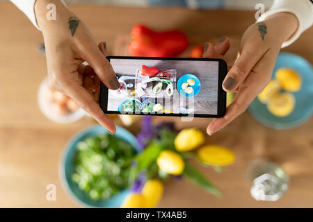 Woman's Hände halten Smartphone, wobei Bild von Gemüse Stockfoto