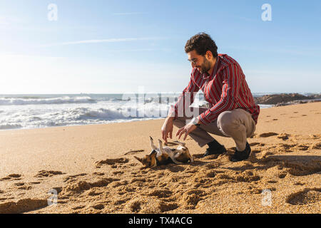 Portugal, Porto, junger Mann spielen am Strand mit seinem Hund Stockfoto