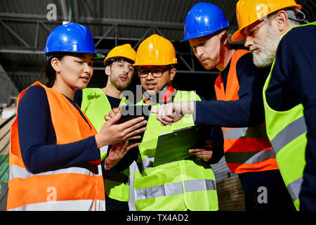 Die Arbeiter in der Fabrik Lager sprechen und mit Tablet Stockfoto