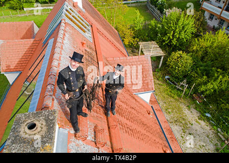 Portrait von zwei lächelnde Schornsteinfeger stehen auf haus dach Stockfoto