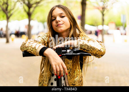 Portrait von Mädchen mit goldenen Pailletten Jacke lehnte sich auf Lenker von E-Scooter Stockfoto