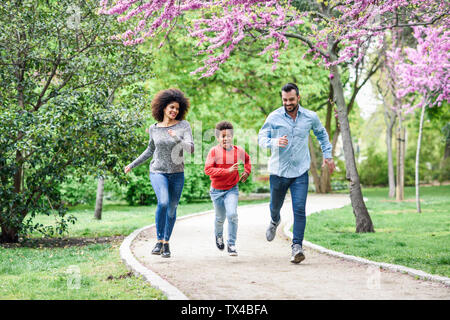 Glückliche Familie laufen und spielen in einem Park Stockfoto