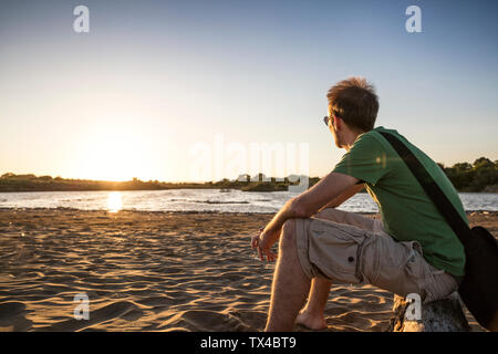 Italien, Sizilien, junger Mann enyoing den Sonnenuntergang am Strand von Eloro Stockfoto