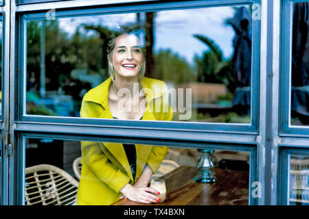 Gerne Frau hinter Fensterglas in einem Cafe Stockfoto