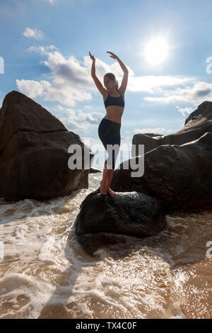 Seychellen, Mahe, Takamaka Beach, reife Frau, die auf einem Felsen an der Hintergrundbeleuchtung Stockfoto