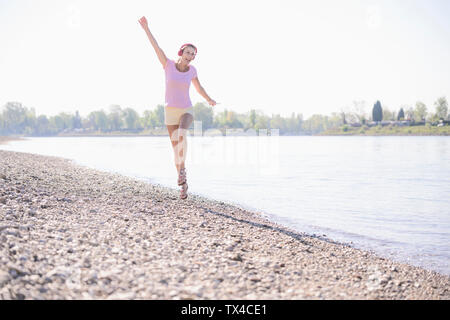 Gerne reife Frau Musikhören mit Kopfhörern am Flußufer Stockfoto