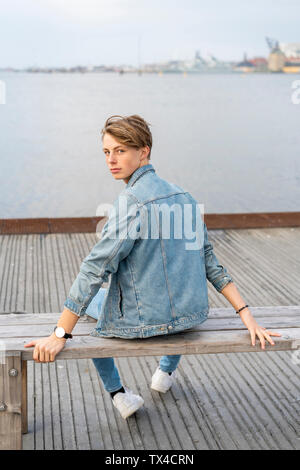 Dänemark, Kopenhagen, jungen Mann sitzen auf einer Bank an der Uferpromenade Stockfoto