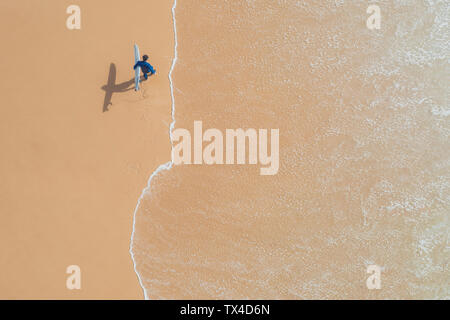 Portugal, Algarve, Lagos, Praia da Mareta, Luftaufnahme von Mann surfboard Durchführung am Strand Stockfoto