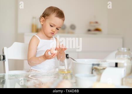 Mädchen, die einen Kuchen in der Küche zu Hause knacken ein Ei Stockfoto