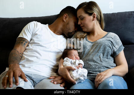 Eltern Kuscheln mit neugeborenen Babys auf der Couch Stockfoto