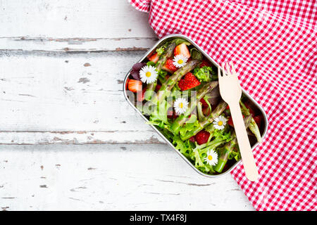 Brotdose mit grünem Salat, grüner Spargel, Erdbeeren und Gänseblümchen Stockfoto