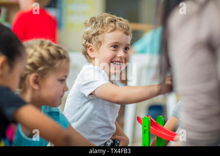 Happy Boy mit anderen Kindern und Pre-school Lehrer im Kindergarten Stockfoto