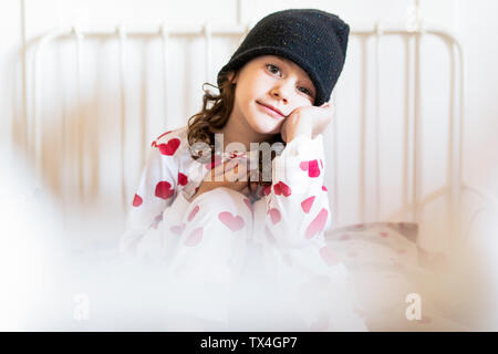 Portrait von kleinen Mädchen im Bett sitzen, tragen, Kappe und Pyjama Stockfoto