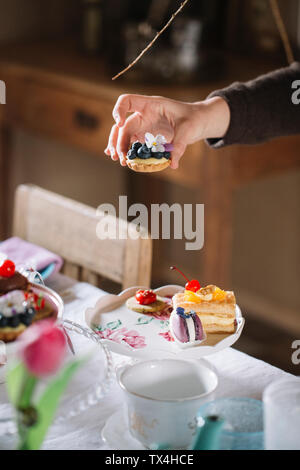 Woman's Hand Anordnen von Gebäck auf Kuchen stand Stockfoto