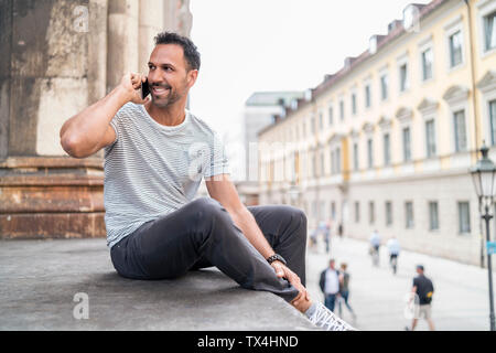 Lächelnder Mann mit Handy in der Stadt Stockfoto