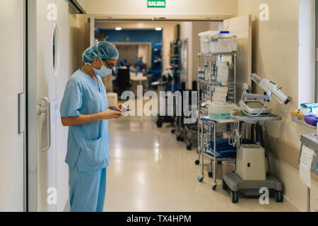 Ärztin mit im Krankenhaus, Smartphone, Vorbereitung für die Chirurgie Stockfoto