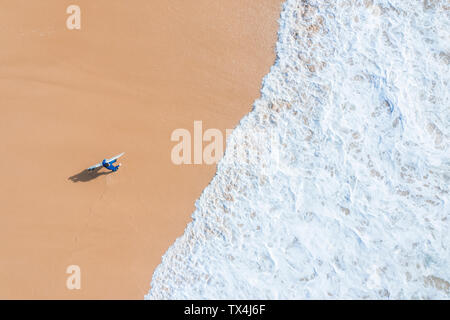 Portugal, Algarve, Lagos, Praia da Mareta, Luftaufnahme von Mann surfboard Durchführung am Strand Stockfoto