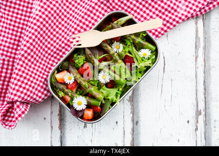 Brotdose mit grünem Salat, grüner Spargel, Erdbeeren und Gänseblümchen Stockfoto