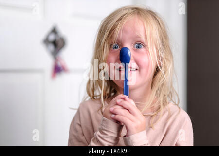 Portrait von lächelnden Mädchen spielen mit blauem Löffel Stockfoto