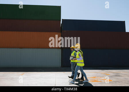 Arbeitnehmer zusammen gehen in der Nähe von Stack von Frachtcontainern auf Industrial Site Stockfoto