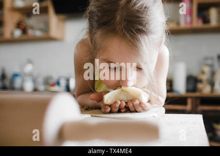 Kleines Mädchen riecht frisch zubereitete gefüllte Backwaren Stockfoto