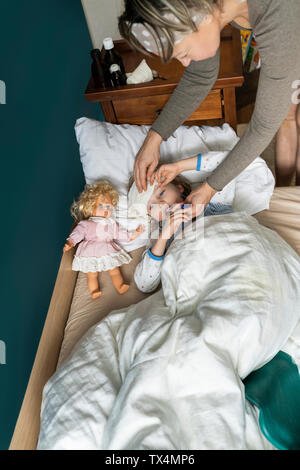 Mutter, die Temperatur der kranken Tochter im Bett liegend Stockfoto