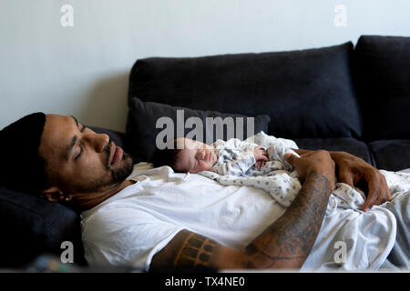 Vater mit neugeborenen Babys schlafen auf der Couch Stockfoto