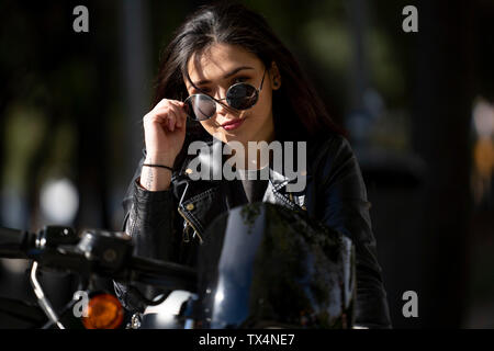 Porträt der jungen Frau Motorradfahrer mit Sonnenbrille und schwarzem Leder Jacke Stockfoto