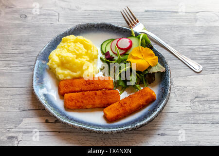 Fischstäbchen mit Kartoffelbrei, Salat mit essbaren Blüten Stockfoto