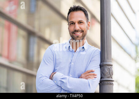 Portrait von zuversichtlich Geschäftsmann gegen einen Laternenpfahl in der Stadt schiefen Stockfoto