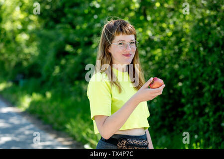 Porträt der jungen Frau mit Brille, mit einem Apfel Stockfoto
