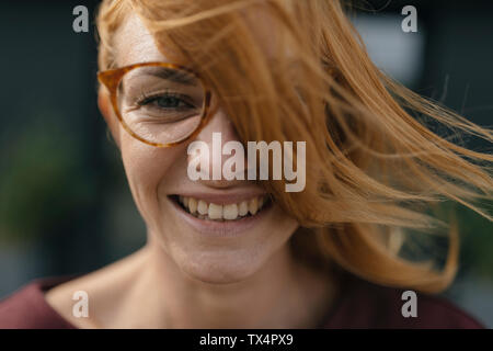 Porträt der glückliche junge Frau mit Brille und windgepeitschten Haar Stockfoto