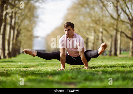 Junger Mann tun Gymnastik Akrobatik in einem städtischen Park Stockfoto