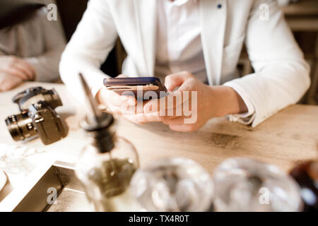 Junger Mann im Restaurant sitzen, mit Smartphone, in der Nähe Stockfoto