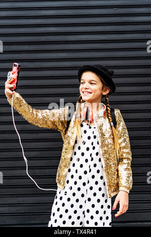 Portrait von lächelnden Mädchen mit Hut und goldenen Pailletten Jacke unter selfie mit Smartphone Stockfoto